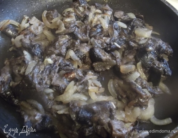Замороженные грибы (у меня лесные) выложить в сковороду с растительным маслом. На сильном огне под крышкой обжарить до испарения жидкости. Посолить, поперчить, добавить нарезанную луковицу. Обжарить до золотистого цвета.