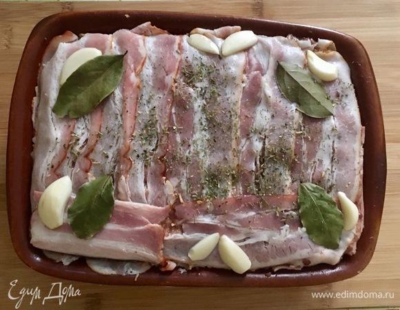 Накрыть оставшимися полосками грудинки. Сверху разложить лавровые листики, чеснок нарезанный пополам, и посыпать тимьяном.
