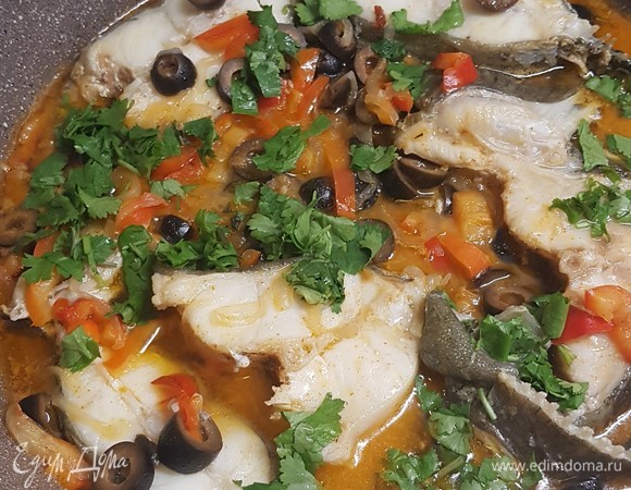 На другой сковороде стейки рыбы обжарить с одной стороны. Потом их перевернуть, залить лимонно-овощной смесью и тушить 10 минут. До окончания тушения добавить зелень кинзы. Подавать с любимым гарниром.