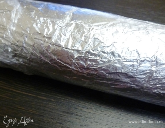 Завернуть фарш в несколько слоев фольги, сформировав круглый рулетик. Фольгу лучше смазать растительным маслом, чтобы фарш не прилипал. Если у вас есть пленка пригодная для запекания, то применить ее. Можно использовать пакеты для запекания. Разогреть духовку до 180°C. В глубокий противень налить горячей воды и положить в него колбасу. Вода должна покрывать колбасу примерно до половины. Готовить минут 45–60, все зависит от размера и толщины колбасы.