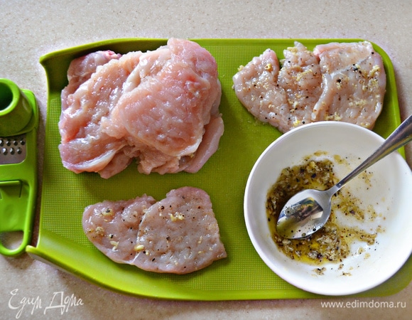 Для маринада необходимо измельчить чеснок, добавить соль, молотый перец и натертый на мелкой терке небольшой кусочек имбиря. Добавить оливковое масло и перемешать. Смазать куриные медальоны полученной смесью, сложить в миску, накрыть пищевой пленкой и оставить мариноваться на 1 час.