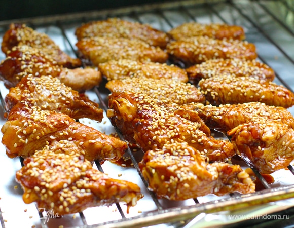 Противень застелить фольгой, над ним установить решетку. На решетку выложить крылья (без маринада), сверху присыпать кунжутом.