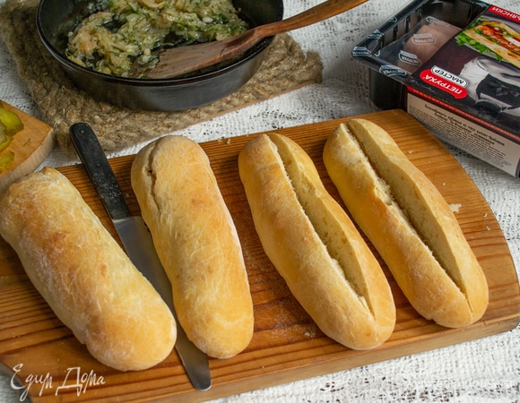 Собираем хот-доги. Делаем продольный разрез на булочках, до конца не прорезаем, иначе начинка выпадет. Чтобы в булочку влезло больше начинки, можно вырезать небольшой клинышек по всей длине.