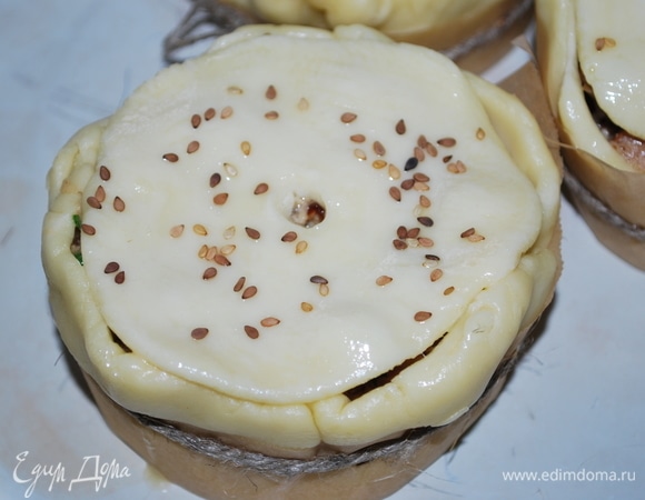 Из теста раскатайте крышечки. Накройте пироги, положив крышки на начинку. Смажьте пироги взбитым яйцом и посыпьте кунжутом (по желанию). Выпекайте примерно 35–40 минут до золотистого цвета.
