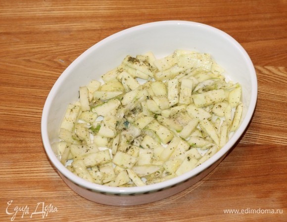 Форму для запекания смазываем маслом и выкладываем мелко нарезанный кабачок. В основном это остатки кабачка или некондиционные кусочки. Посыпаем кабачки сухой приправой (орегано) и солим. На кабачки кладем рулетики.