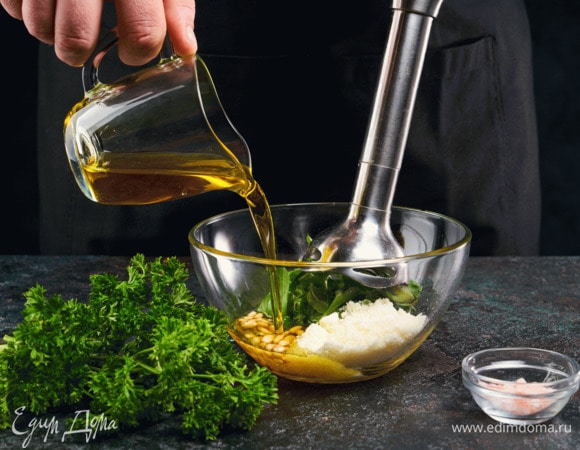 Приготовьте соус песто. Чеснок почистите. Твердый сыр натрите на терке. В чашу блендера выложите сыр, чеснок, обжаренные кедровые орехи, петрушку, базилик и оливковое масло. Пробейте блендером.