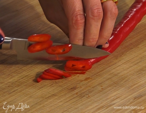 Перец чили очистить от семян, тонко нарезать, добавить на сковороду.