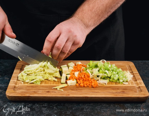 Лук нарежьте полукольцами, сельдерей — средними дольками, морковь нарежьте мелкими кубиками, чеснок мелко порубите, нашинкуйте савойскую капусту. Цукини почистите и нарежьте средними кубиками.