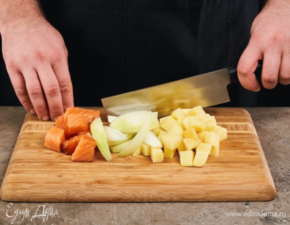 Лук почистите и нарежьте дольками, картофель почистите и нарежьте кубиками. С лосося снимите шкурку и нарежьте кубиками 2х2 см.