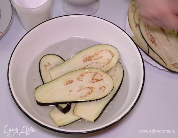 Сначала лучше избавить баклажаны от горечи. Есть несколько способов, но я обычно кладу полоски баклажанов в миску с подсоленной водой примерно на полчаса. Понадобится 1 столовая ложка соли на литр воды.