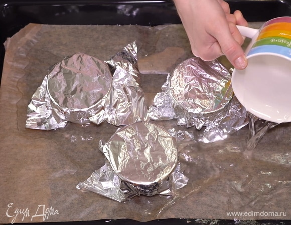 Перекладываем формы для выпекания на противень и наливаем сюда воду так, чтобы она доходила до середины формы. То есть мы будем выпекать десерт на водяной бане. Отправляем десерт в разогретую до 180°C духовку на полчаса.