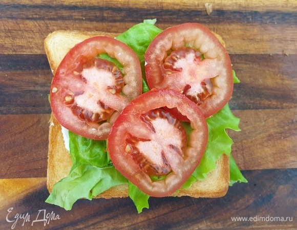 На сыр кладем еще один кусок хлеба, смазанный соусом, лист салата, кружки помидора.