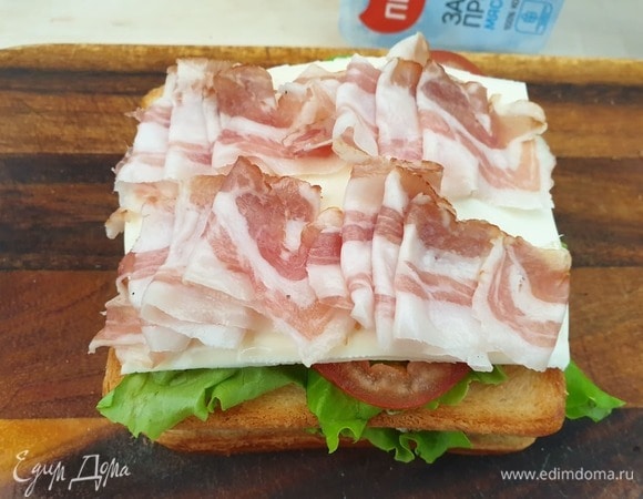 На помидоры кладем пластинку сыра и сырокопченый бекон.