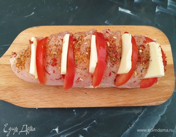 В каждый надрез вставляем половину кругляшка помидора и моцареллу.