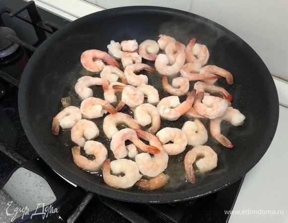 Снимаем лук и обжариваем креветки до готовности. Я использовала замороженные. Как только они немного оттают, добавляем рубленный чеснок.