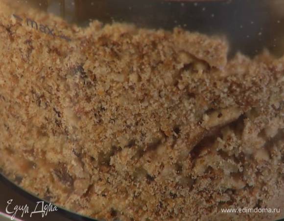 Сухари и чеснок выложить в чашу блендера и измельчить, затем всыпать грецкие орехи и снова измельчить, добавить кедровые орехи, пармезан и на высокой скорости взбить все в мелкую крошку.