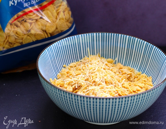 Кукурузные хлопья слегка растолочь, можно положить в пакет и побить молотком. Насыпать измельченные кукурузные хлопья в широкую миску и добавить к ним натертый на мелкой терке пармезан и луковые хлопья. Можно добавить чеснок сухой порошком и паприку сушеную для интенсивности цвета корочки. Как следует перемешать эту сухую смесь.