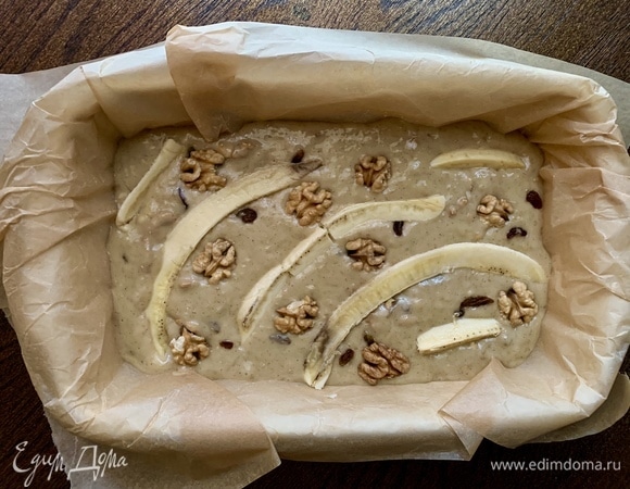 Духовка — на 175°C. Форму накрываю пергаментом, можно сделать французскую рубашку, если нет пергамента. Тесто — в форму. Банан — на полоски.  Украшаю пирог, орехи для красоты — туда же.