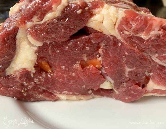 Морковь и чеснок очистить. Нарезать, добавить розмарин и нашпиговать мясо.