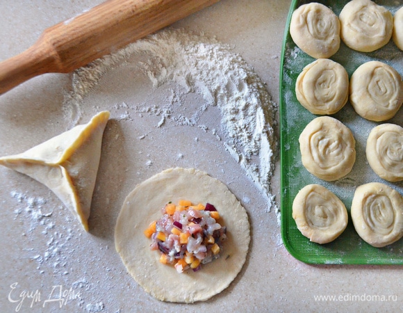 Затем каждый кусочек теста аккуратно и равномерно раскатайте до толщины 1–2 мм. В середину круга положите начинку и соедините края, чтобы получился треугольник.