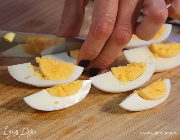 Яйца разделить на дольки. Нарезать укроп и петрушку.