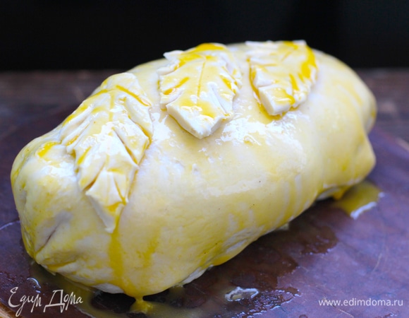 Сложить каждый край к центру, потом еще раз подвернуть с боков выступающие треугольники теста. Заготовка должна стать похожа на плотно спеленатого младенца. Перевернуть заготовку швом вниз, смазать желтком и сверху украсить фигурками из обрезков теста.