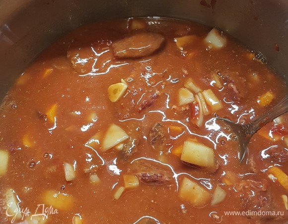 В кастрюле с толстым дном смешать мясо с луком, морковью и чесноком. Добавить томатную пасту. Влить темное пиво и 200 мл воды. Довести до кипения, потом убавить огонь до минимума и тушить мясо 1,5 часа.