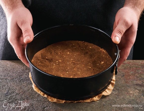 Дно разъемной формы застелите пергаментом, выложите сливочную крошку, равномерно распределите по дну. Поставьте в духовку, разогретую до 180°С, на 10–15 минут.