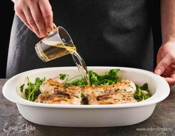 В форму выложите цыпленка, налейте белое вино. Добавьте веточки кинзы и зубчики чеснока.