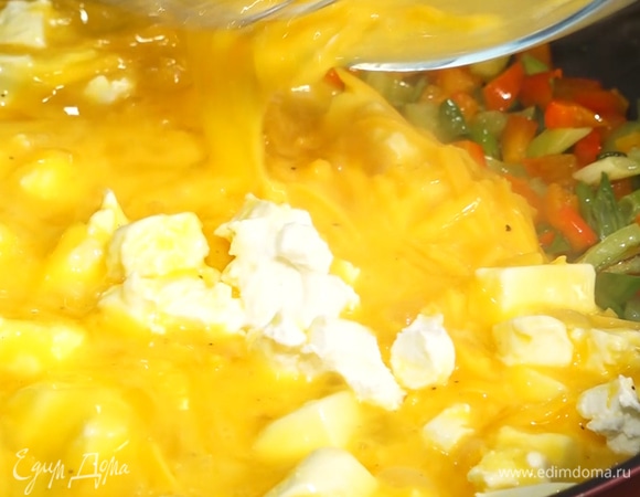 Овощи на сковороде залить яично-сырной массой, перемешать, посыпать оставшимся чеддером.