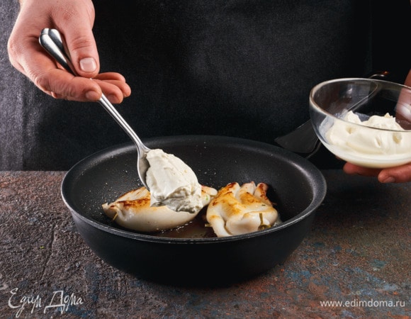 Выложите кальмаров на сковородку, смазанную маслом. Сметаной обильно смажьте тушки. Тушите 2–3 минуты.