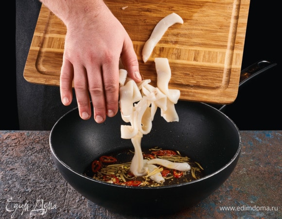 Разогрейте в сковороде оливковое масло, добавьте чеснок, перец чили и имбирь и обжаривайте полминуты. Затем добавьте кальмары. Обжаривайте 1 минуту.