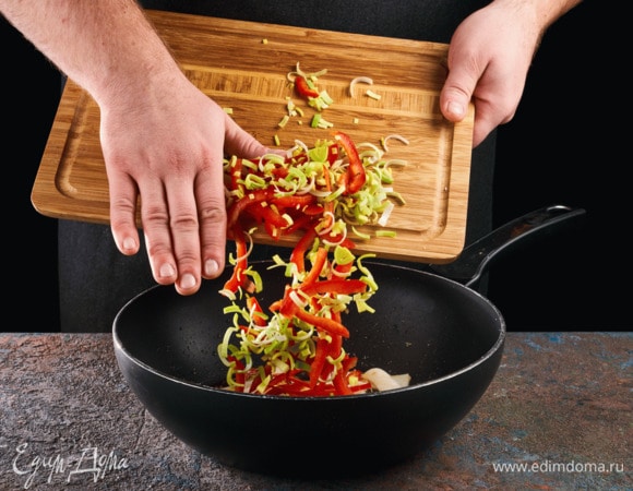 Добавьте нарезанные лук-порей и болгарский перец, обжаривайте 1,5–2 минуты.