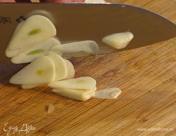 Чеснок нарезать тонкими ломтиками, добавить к луку.  