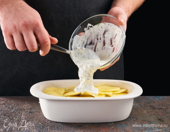 Выложите вторую часть нарезанного лука, еще один ряд картофеля, добавьте сметанный соус. 