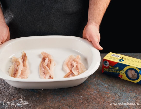 Филе минтая ТМ «Океанрыбфлот» промойте и обсушите бумажным полотенцем. Смажьте форму маслом. Выложите рыбное филе.
