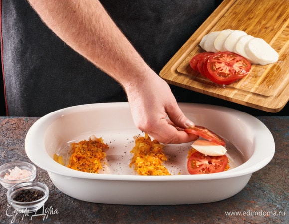 На рыбу выложите обжаренные овощи, потом кружочки помидоров и сыра. Запекайте в духовке 15 минут при 185°С.