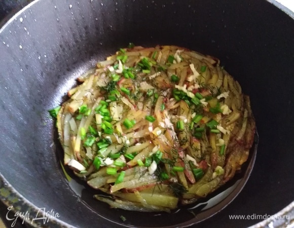 Жарить 10 минут на сильном огне. Посыпать нарезанными специями. Укроп, чеснок и зеленый лук. Вилкой немного придавить их к картофелю.