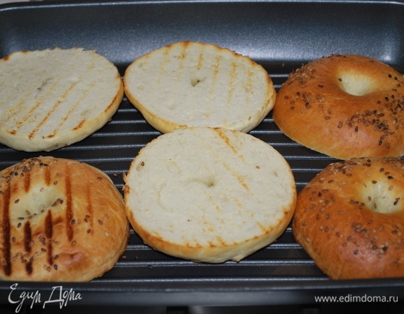 Разрежьте бейглы пополам. Разогрейте сковороду-гриль или включите электрогриль.