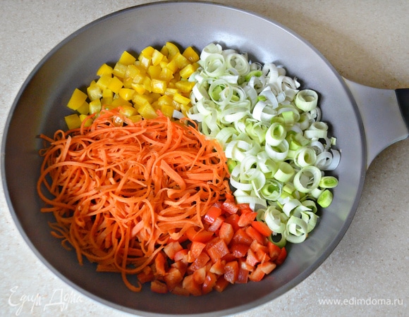 Морковь натрите на терке для корейской моркови или нарежьте очень тонкими полосками, лук–порей нарежьте тонкими кружочками, перец — мелкими кубиками. Овощи слегка обжарьте в сковороде на сливочном масле до мягкости.