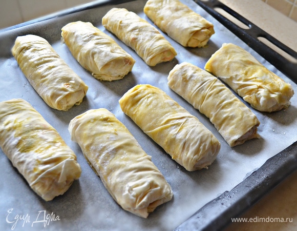 Противень застелите пекарской бумагой, смажьте поверхность маслом и выложите рулеты. Сверху рулеты так же смажьте растопленным маслом. Выпекайте 30–35 минут в разогретой до 180°C духовке до золотистого цвета.