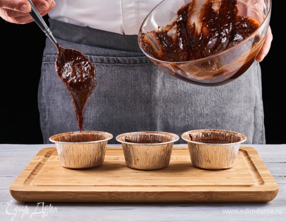 Заранее разогрейте духовку до 200°C. Смажьте формочки для кексов растительным маслом и слегка посыпьте какао-порошком. Наполните формы тестом и отправьте в духовой шкаф на 9 минут.
