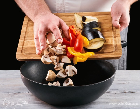 Нарежьте на кусочки болгарский перец, баклажан и грибы, отправьте все на сковороду и обжарьте на растительном масле.