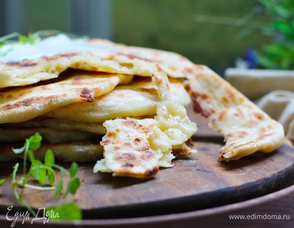 Выложить лепешки с сыром на сковороду. Подрумянивать примерно 2 минуты с одной стороны. После подрумянивания одной стороны, перевернуть лепешки на другой сторону и жарить до румяности. Готовые лепешки сложить друг на друга, накрыть салфеткой, дать немного остыть и подавать с кефиром и зеленью.