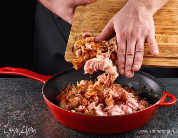 Бекон нарежьте на кусочки, добавьте его к зажарке вместе с отделенным от косточек мясом. Посолите, поперчите. Обжаривайте 10 минут.
