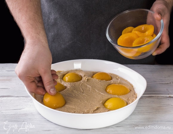 Сверху выложите по кругу персики. Выпекайте в духовке при 180°С около 45–50 минут. 