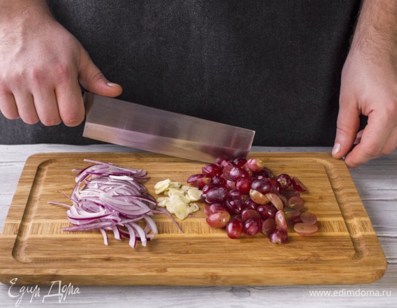 Креветки разморозьте и очистите. Чеснок порубите тонкими слайсами, лук нарежьте полукольцами. виноград разрежьте пополам.