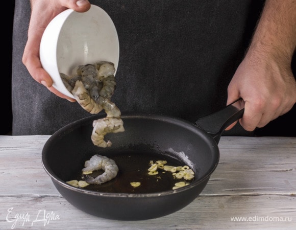 На сковороду налейте масло и обжарьте чеснок. Добавьте креветки и обжаривайте до готовности 3 минуты.