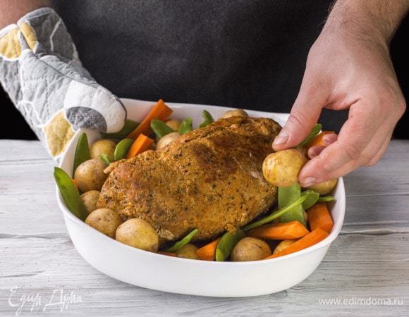 Через полтора часа достаньте из духовки, уберите фольгу, выложите по бокам буженины беби-картофель, морковь и стручки гороха. Полейте их маслом и поставьте в духовку еще на 20 минут.