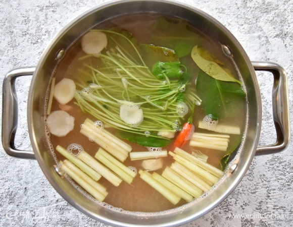 Добавить в бульон стебли кинзы, корень галангала, очищенный и нарезанный шайбочками, стебли лемонграсса, раздавленные ножом для большего аромата, листья каффир-лайма и чили, разрезанный вдоль, с удаленными семенами.
